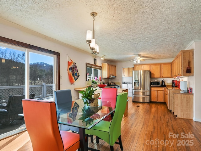 dining room featuring a textured ceiling, light hardwood / wood-style flooring, ceiling fan, and washing machine and clothes dryer