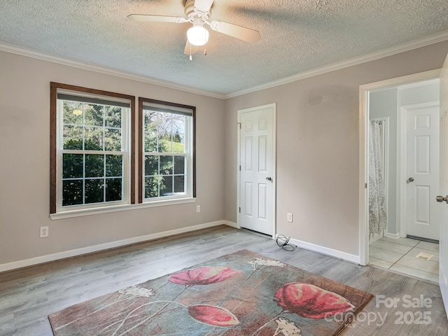 unfurnished room featuring a textured ceiling, light hardwood / wood-style floors, ceiling fan, and crown molding