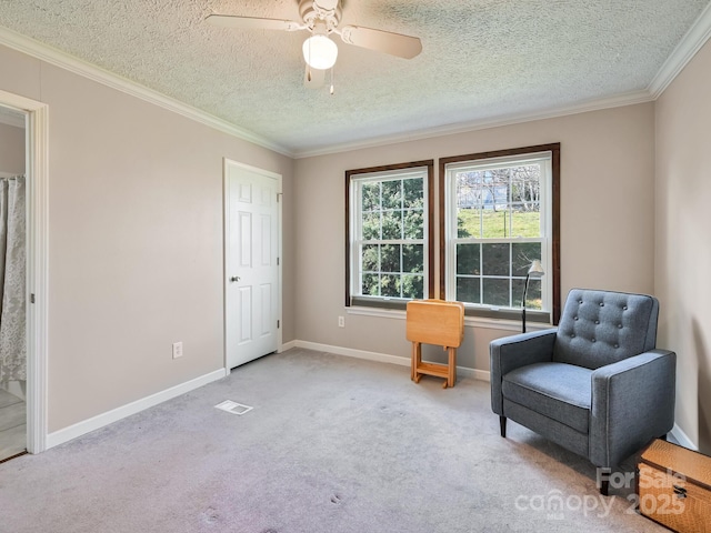 living area with a textured ceiling, light colored carpet, ceiling fan, and crown molding