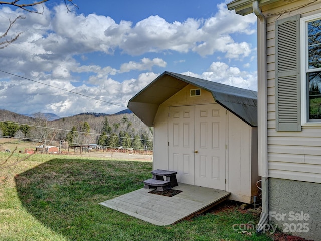 view of outdoor structure with a mountain view and a yard