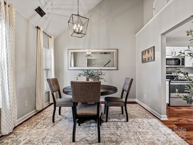 dining area featuring hardwood / wood-style flooring, a chandelier, and vaulted ceiling