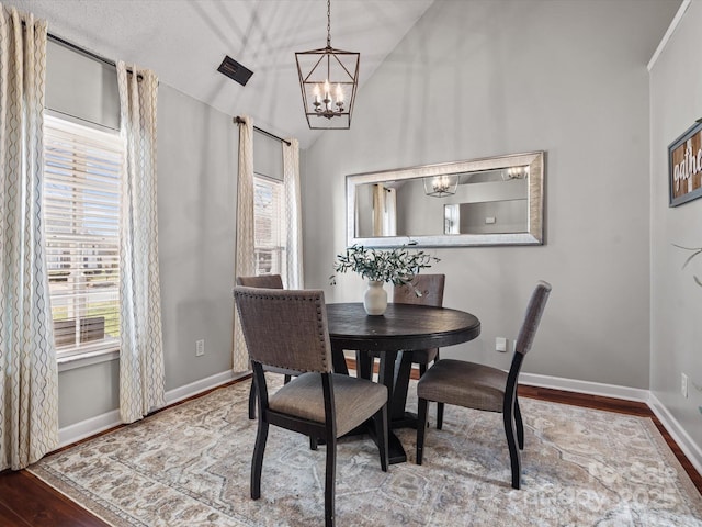 dining room featuring lofted ceiling, hardwood / wood-style flooring, a chandelier, and a wealth of natural light