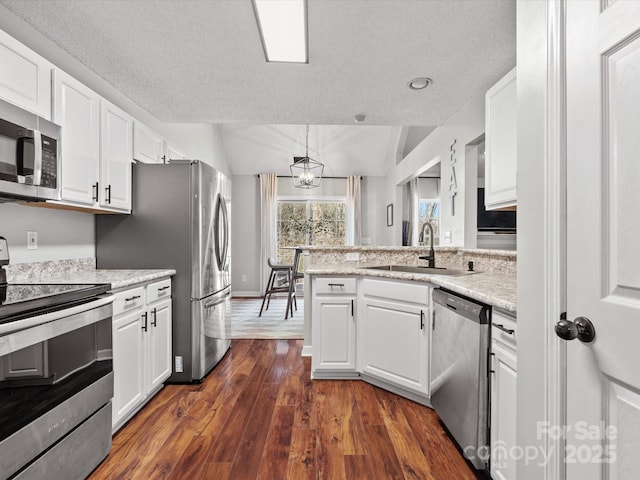 kitchen featuring stainless steel appliances, sink, white cabinets, hanging light fixtures, and dark hardwood / wood-style floors