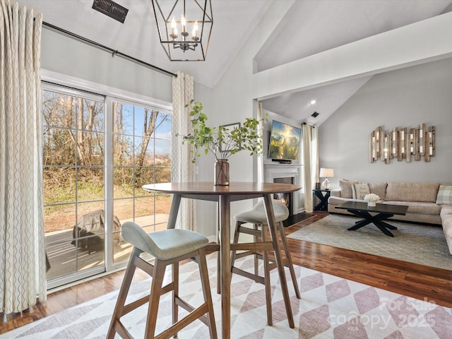 dining area with lofted ceiling, a chandelier, and light wood-type flooring