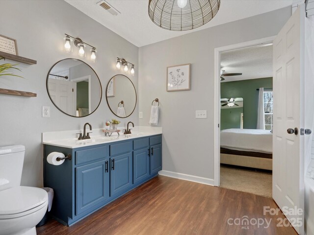 bathroom featuring hardwood / wood-style floors, toilet, vanity, ceiling fan, and a textured ceiling