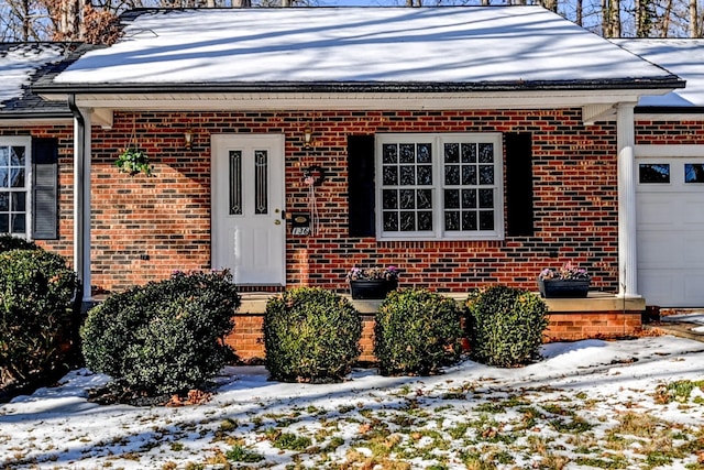 snow covered property entrance featuring a garage