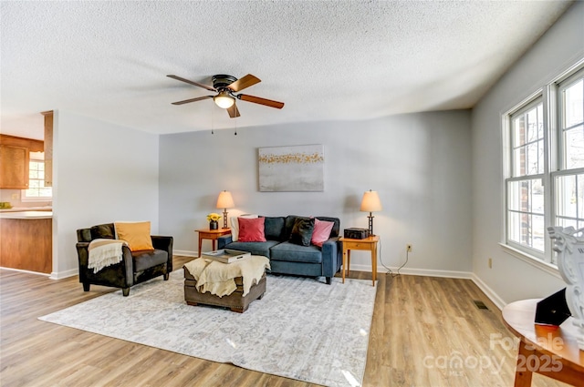 living room with a textured ceiling, light hardwood / wood-style floors, and ceiling fan