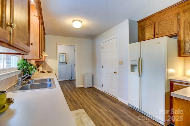 kitchen featuring sink, dark hardwood / wood-style floors, white fridge with ice dispenser, a textured ceiling, and range hood