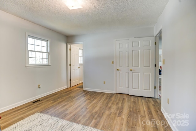 unfurnished bedroom featuring hardwood / wood-style floors, a textured ceiling, and a closet