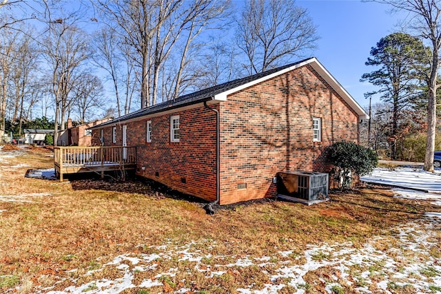 view of snowy exterior featuring a yard, central AC unit, and a deck