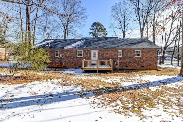 snow covered back of property with a deck