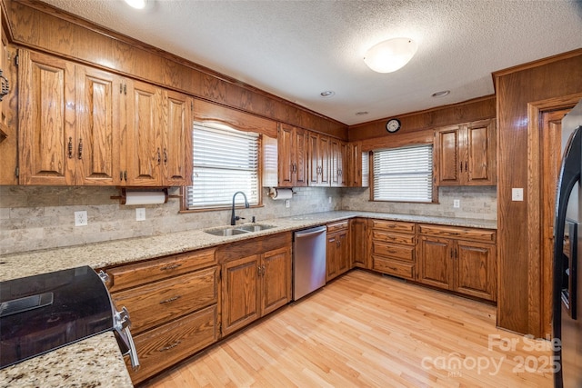 kitchen featuring light stone counters, stainless steel dishwasher, a healthy amount of sunlight, and sink