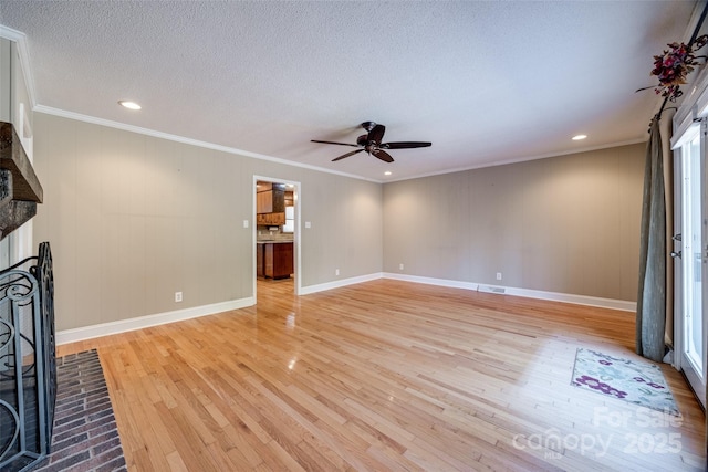 unfurnished living room featuring a brick fireplace, ornamental molding, a textured ceiling, ceiling fan, and light hardwood / wood-style floors