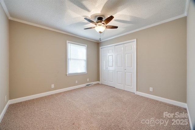 unfurnished bedroom featuring carpet floors, a closet, ceiling fan, and crown molding