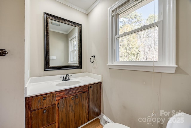 bathroom with toilet, vanity, and ornamental molding