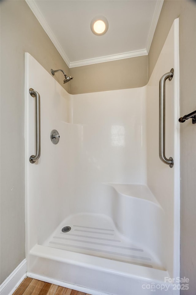 bathroom with hardwood / wood-style floors, a shower, and ornamental molding