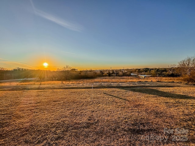 yard at dusk featuring a rural view