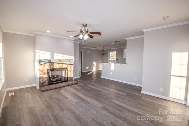 unfurnished living room with ceiling fan, a stone fireplace, dark hardwood / wood-style flooring, and ornamental molding