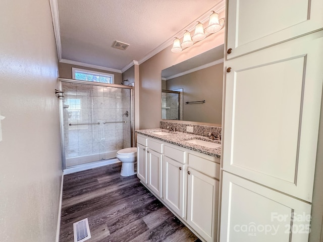 bathroom featuring vanity, a textured ceiling, wood-type flooring, toilet, and a shower with shower door