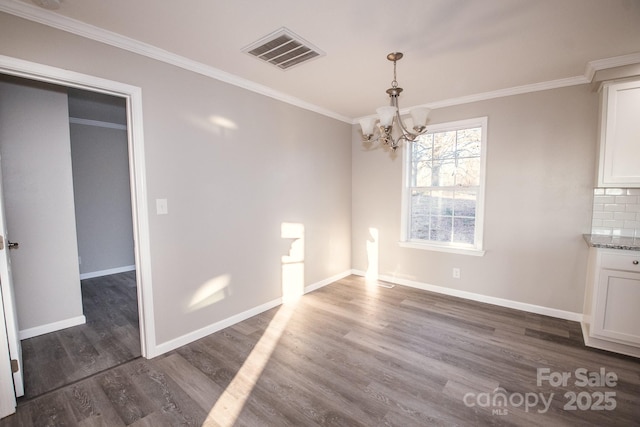 unfurnished dining area featuring a chandelier, crown molding, and dark wood-type flooring