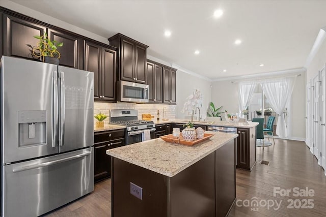 kitchen with a peninsula, a center island, dark brown cabinets, appliances with stainless steel finishes, and decorative backsplash