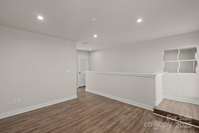 empty room with recessed lighting, wood finished floors, and baseboards