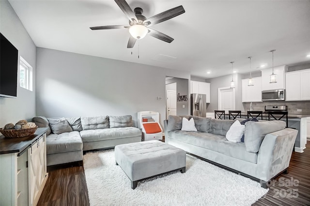 living room with ceiling fan and dark wood-type flooring