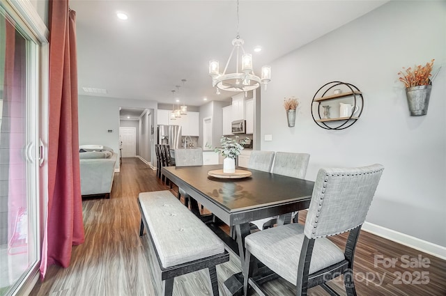 dining room with dark hardwood / wood-style flooring and an inviting chandelier