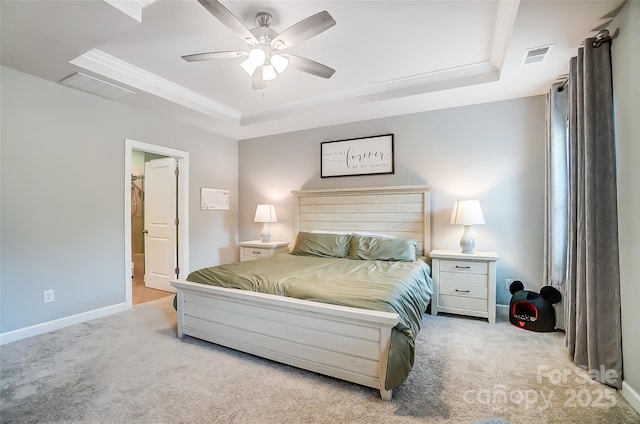 carpeted bedroom featuring a raised ceiling, ensuite bath, ceiling fan, and crown molding