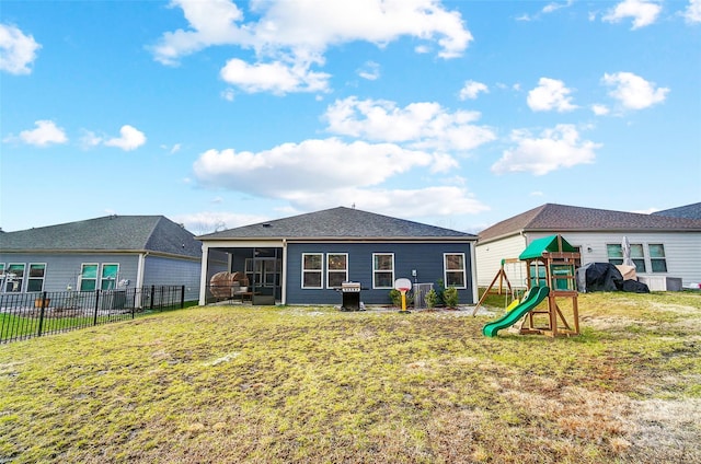 rear view of property featuring a sunroom, a playground, and a yard