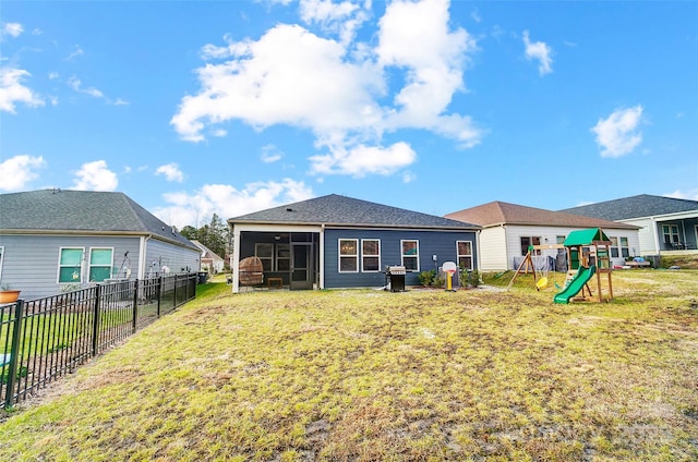 back of house with a playground, a sunroom, and a lawn