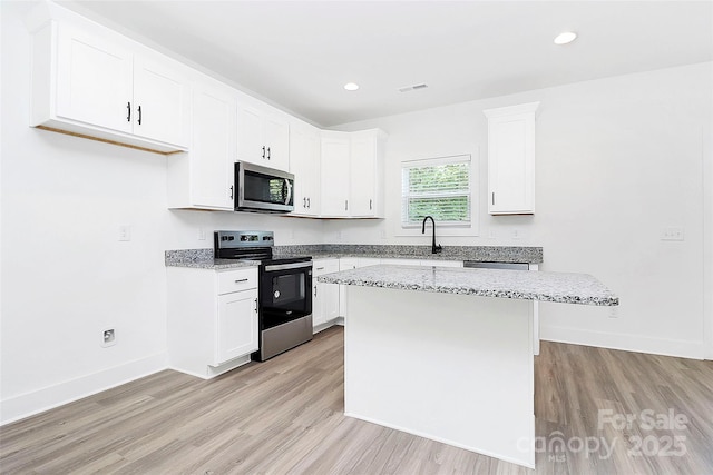 2365 28th St NE, Hickory, NC 28601 - kitchen featuring appliances with stainless steel finishes, a center island, light stone counters, and light wood-type flooring