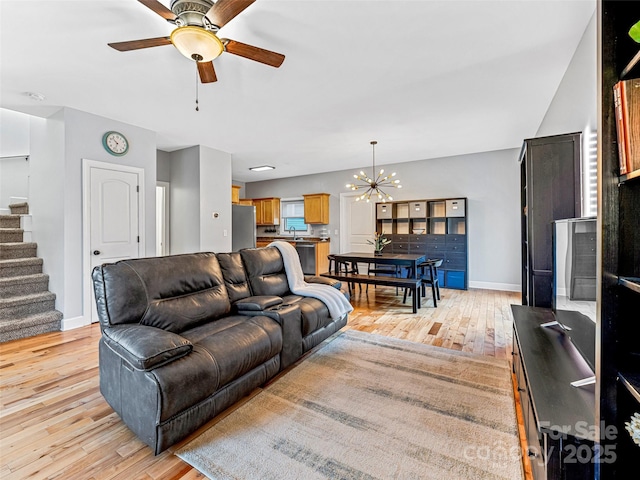 living room featuring light hardwood / wood-style flooring and ceiling fan with notable chandelier