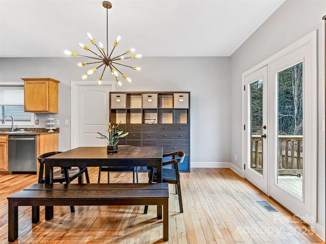 dining room with sink, light hardwood / wood-style flooring, french doors, and a notable chandelier