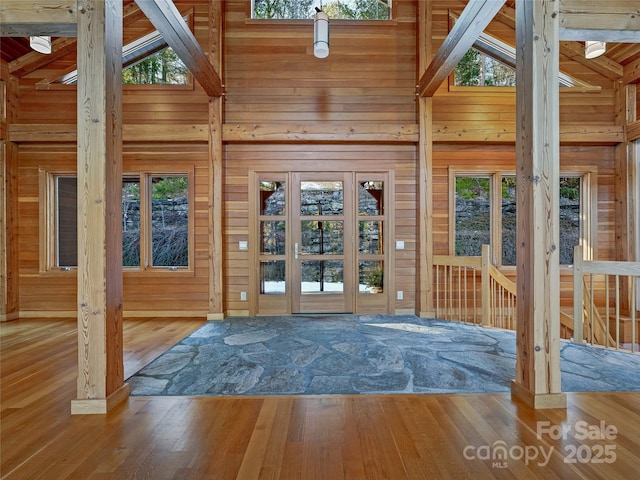 doorway with high vaulted ceiling, a wealth of natural light, beamed ceiling, and hardwood / wood-style flooring