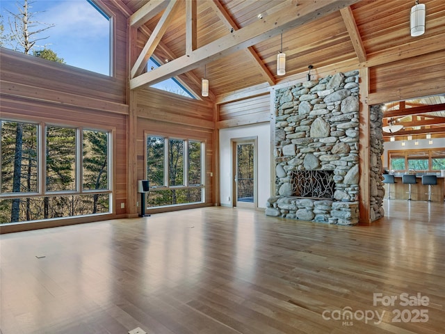 unfurnished living room with beamed ceiling, wood ceiling, a fireplace, and high vaulted ceiling