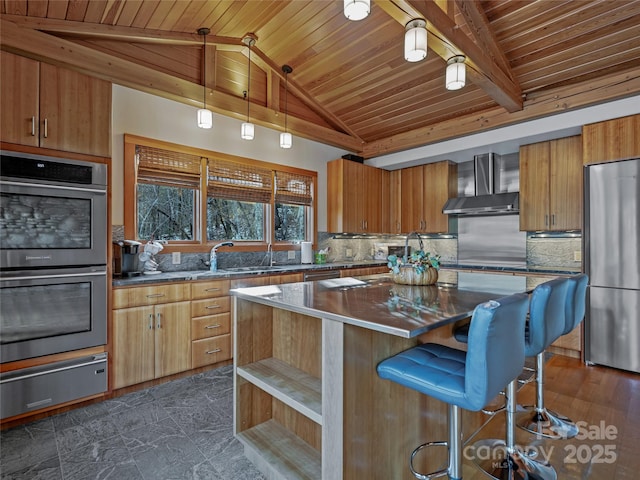 kitchen with decorative light fixtures, a center island, a breakfast bar area, stainless steel appliances, and wall chimney exhaust hood