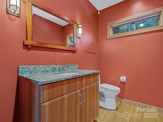 bathroom with toilet, hardwood / wood-style floors, and vanity