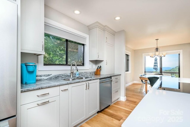 kitchen featuring an inviting chandelier, sink, light hardwood / wood-style flooring, appliances with stainless steel finishes, and white cabinetry