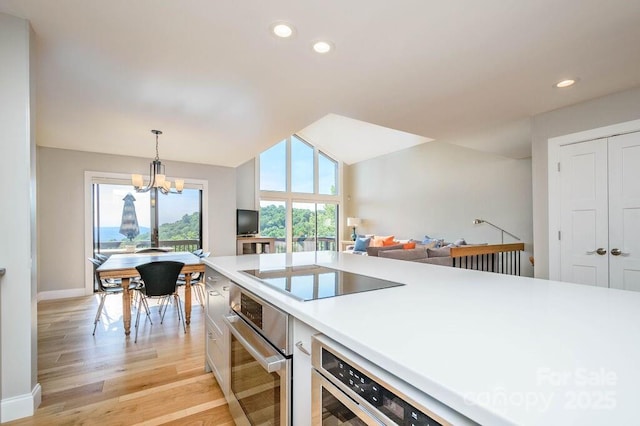 kitchen featuring black electric stovetop, a healthy amount of sunlight, pendant lighting, and stainless steel oven