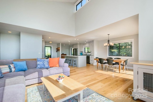 living room featuring plenty of natural light, wine cooler, a high ceiling, and a chandelier