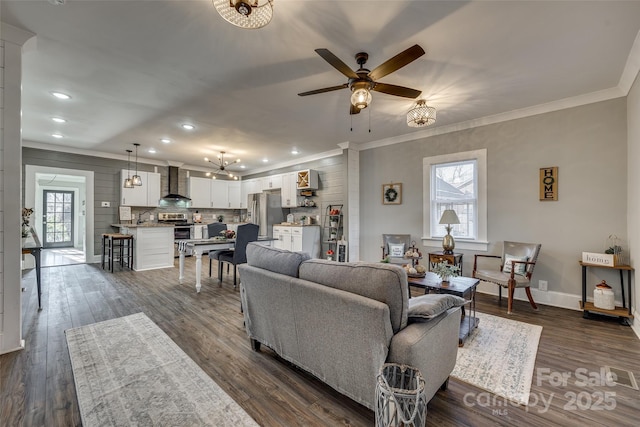 living room with ornamental molding, dark wood-type flooring, and ceiling fan with notable chandelier