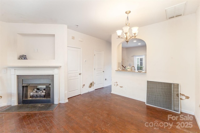 unfurnished living room featuring dark hardwood / wood-style flooring and a chandelier