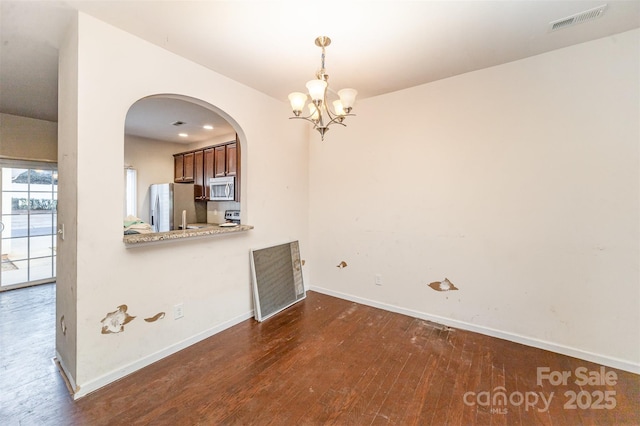 unfurnished dining area featuring dark hardwood / wood-style flooring and an inviting chandelier