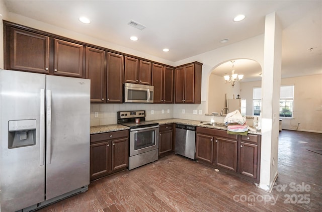 kitchen with appliances with stainless steel finishes, backsplash, light stone counters, and sink