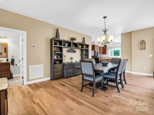 dining area with light hardwood / wood-style floors and a notable chandelier