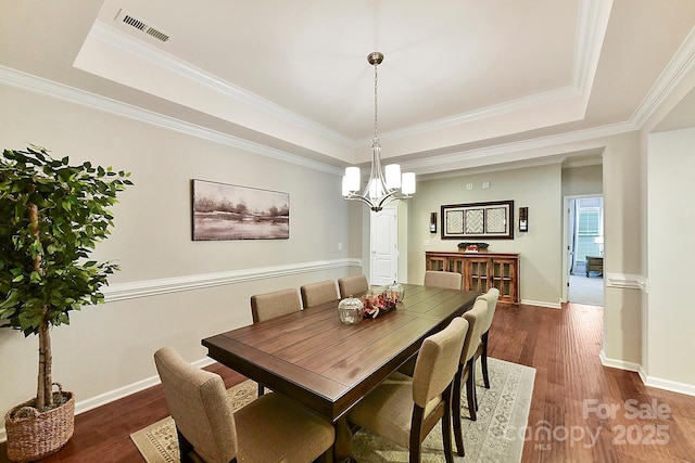 dining room featuring dark hardwood / wood-style floors, a raised ceiling, and ornamental molding