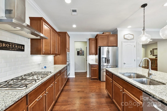 kitchen with light stone countertops, backsplash, stainless steel appliances, sink, and wall chimney range hood