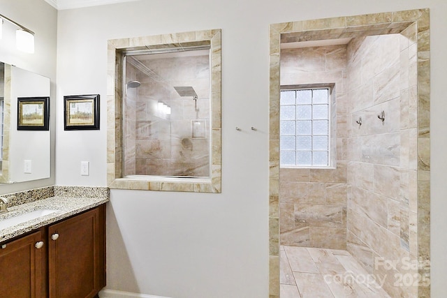 bathroom with a tile shower and vanity