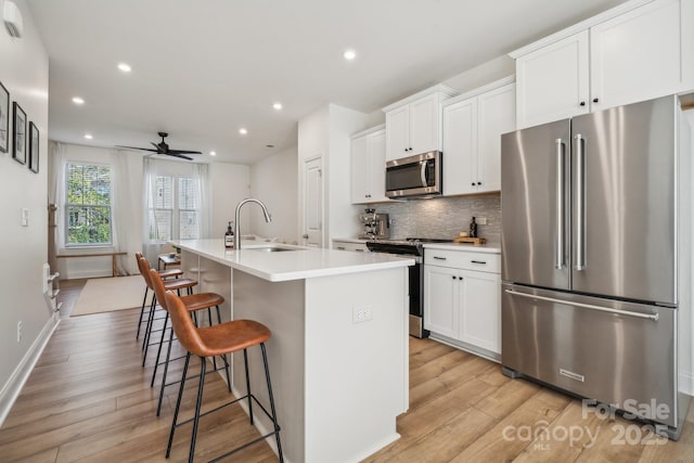 kitchen featuring ceiling fan, sink, a center island with sink, a breakfast bar area, and stainless steel appliances